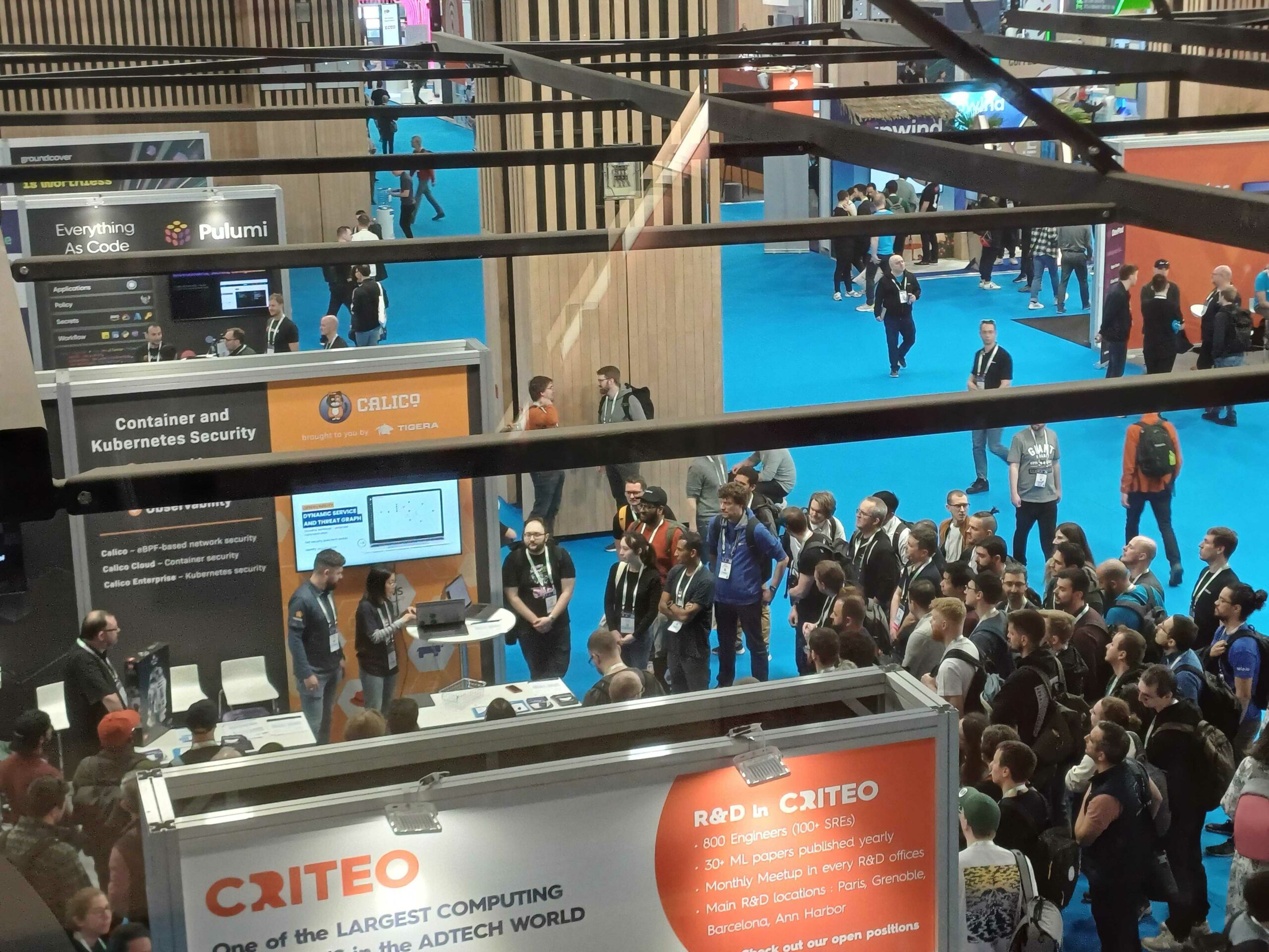 Overhead view of a crowded tech conference trade show floor with numerous booths and attendees