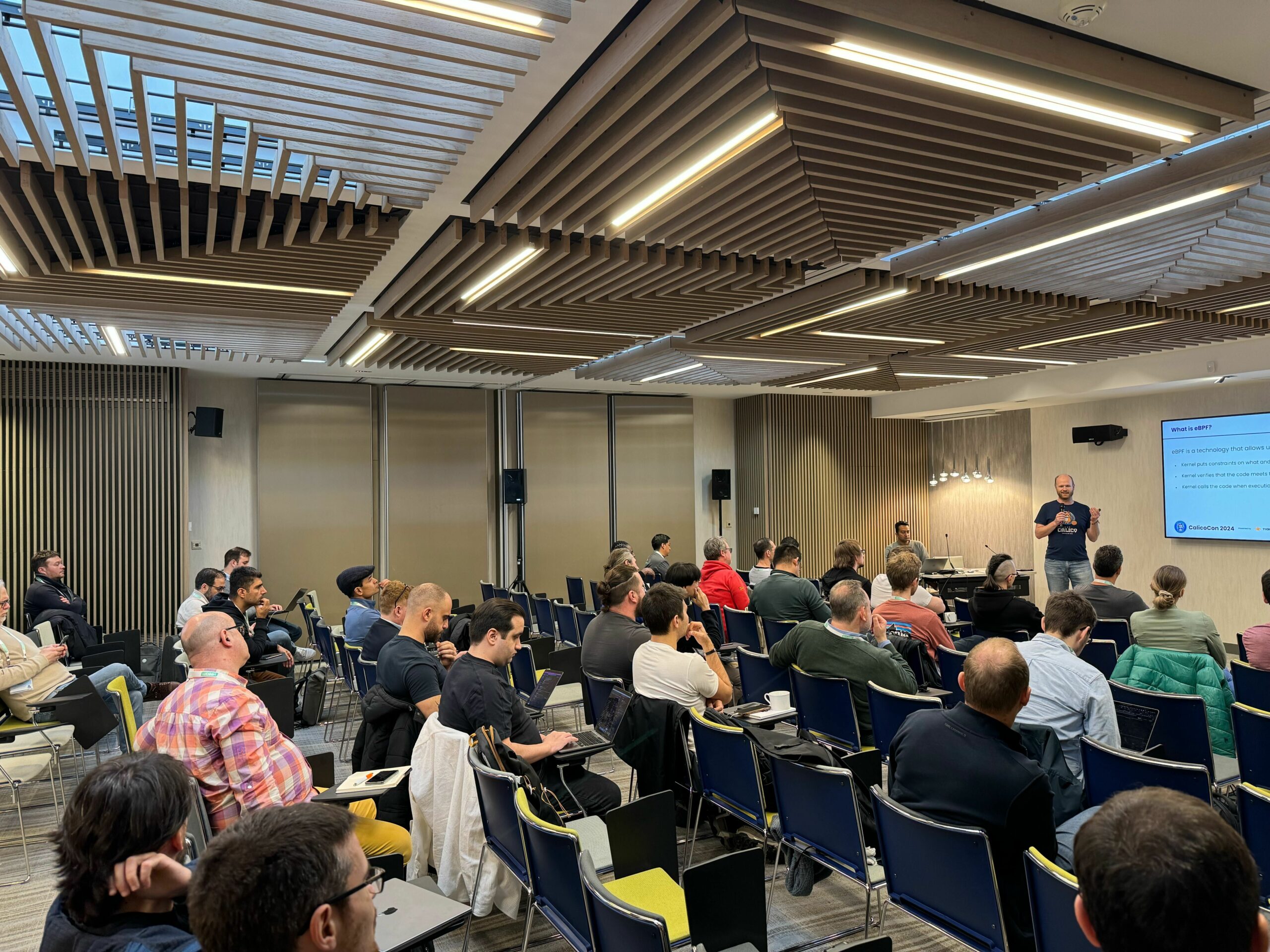 A person giving a presentation to a large audience seated in a conference room