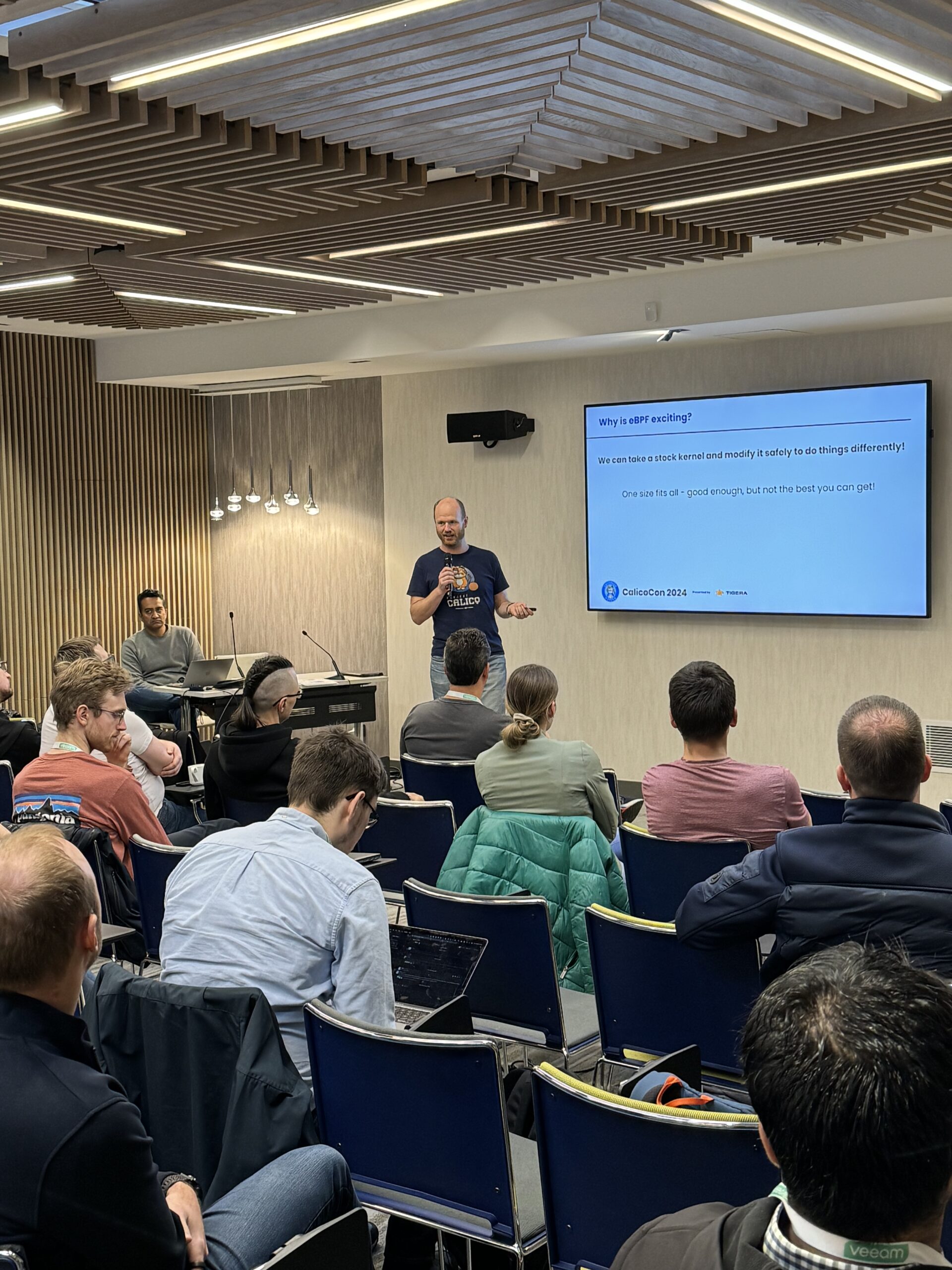 A man gives a presentation to a seated audience about eBPF