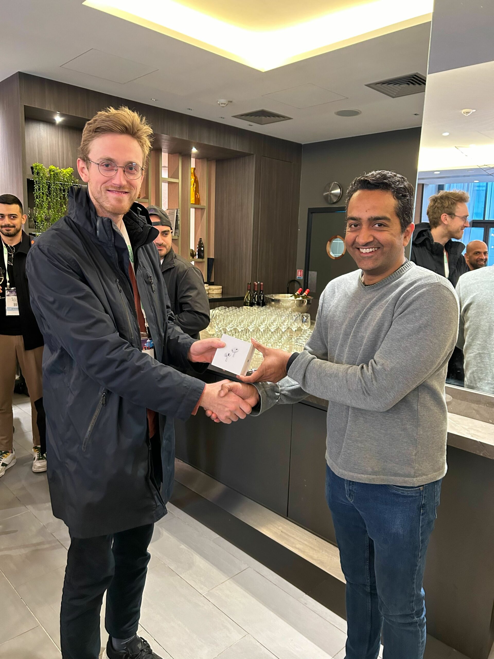 Two people shaking hands, one handing the other a small white box